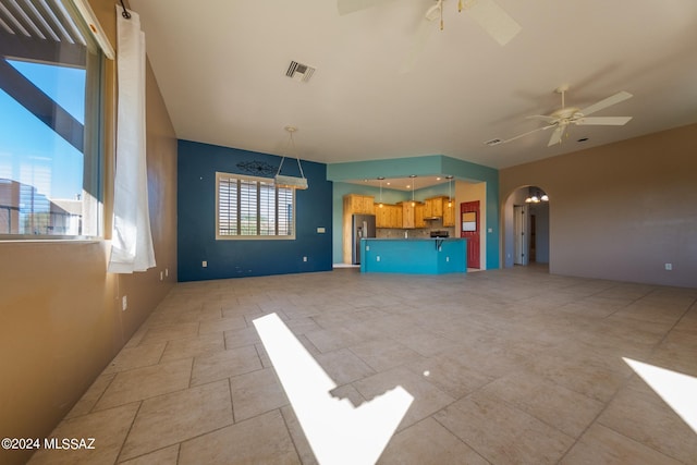 unfurnished living room featuring a healthy amount of sunlight and ceiling fan