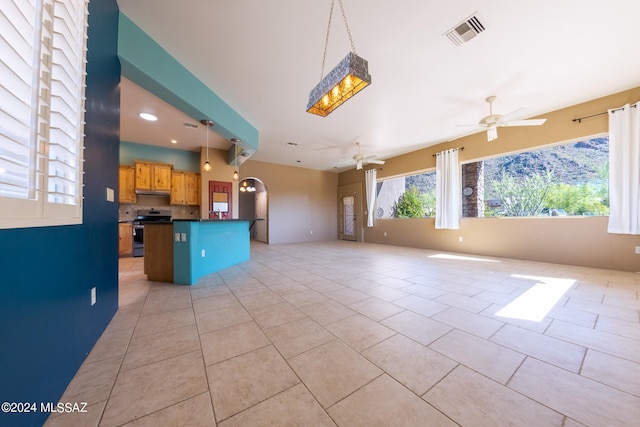 kitchen featuring a kitchen breakfast bar, light tile patterned flooring, stainless steel stove, pendant lighting, and ceiling fan