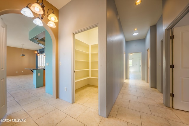 hallway with a notable chandelier and light tile patterned floors