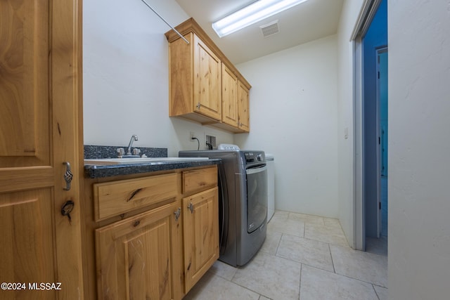 washroom with light tile patterned floors, sink, washing machine and clothes dryer, and cabinets