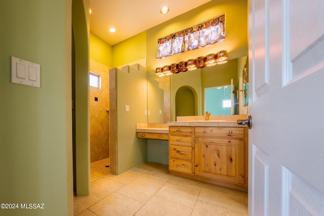 bathroom featuring vanity, plenty of natural light, a tile shower, and tile patterned floors