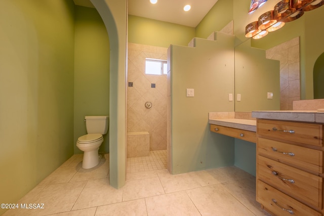 bathroom featuring a tile shower, vanity, tile patterned flooring, and toilet