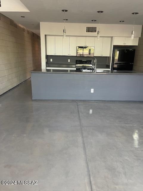 kitchen with refrigerator, white cabinets, range, and concrete flooring