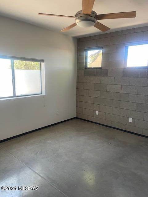 spare room with ceiling fan and concrete floors