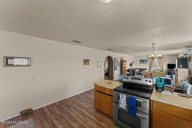 kitchen featuring a wall mounted air conditioner, stainless steel range with electric cooktop, dark wood-type flooring, a textured ceiling, and a notable chandelier