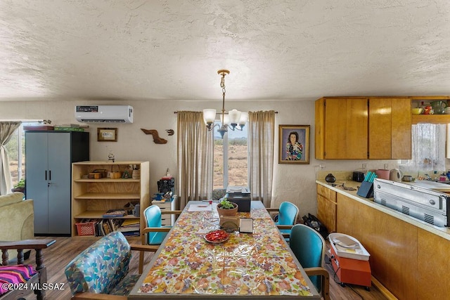 dining area with hardwood / wood-style flooring, a notable chandelier, a textured ceiling, and a wall unit AC