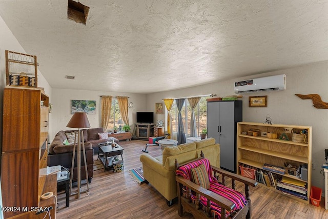 living room with wood-type flooring, a textured ceiling, and an AC wall unit