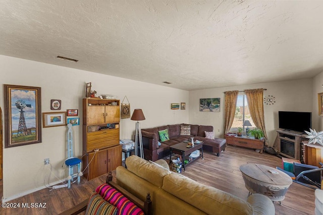 living room featuring a fireplace, a textured ceiling, and hardwood / wood-style flooring