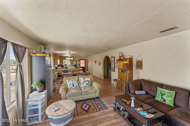 living room featuring wood-type flooring, a textured ceiling, and an AC wall unit