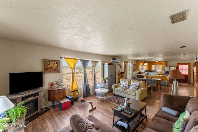 living room with a chandelier, a textured ceiling, and hardwood / wood-style flooring