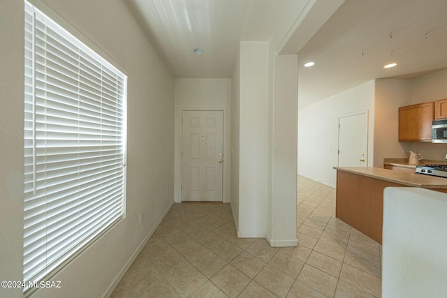 kitchen with light tile patterned flooring, recessed lighting, stove, light countertops, and stainless steel microwave