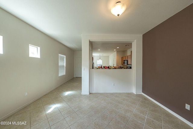 empty room featuring light tile patterned floors and baseboards