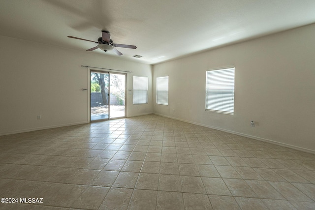 empty room with light tile patterned floors, baseboards, visible vents, and a ceiling fan