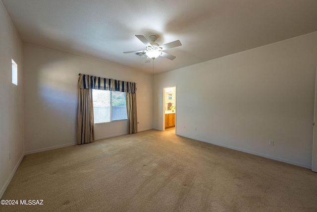 spare room with light carpet, a ceiling fan, and baseboards