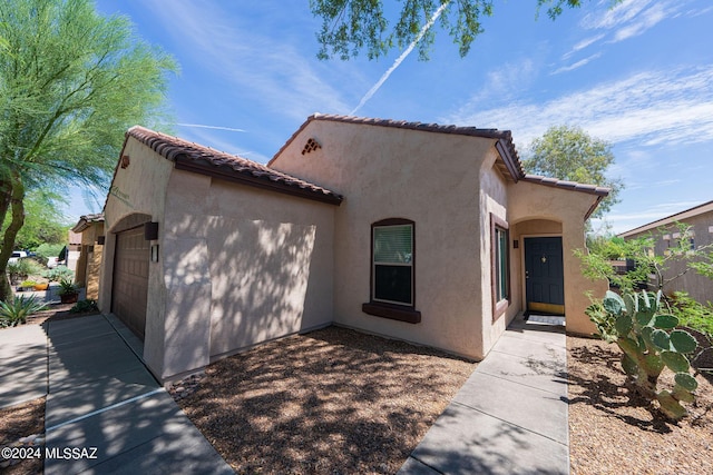 mediterranean / spanish house featuring a tiled roof, an attached garage, and stucco siding