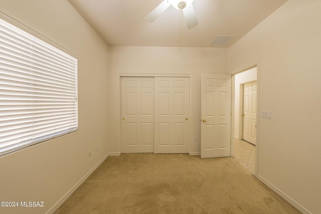 unfurnished bedroom featuring a closet, light colored carpet, visible vents, ceiling fan, and baseboards