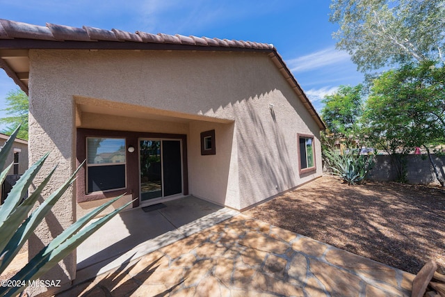 back of property with a tiled roof, a patio, fence, and stucco siding