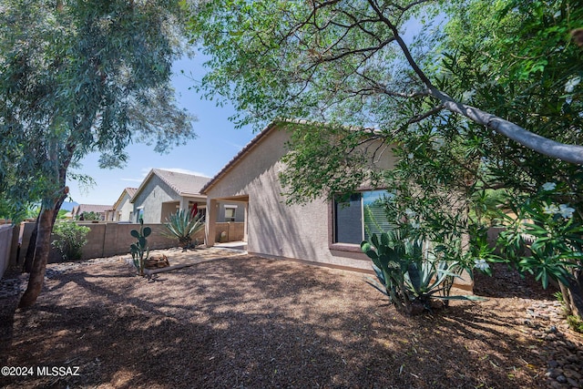 rear view of property with fence private yard, a tiled roof, a patio area, and stucco siding