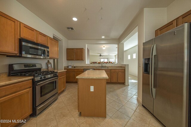 kitchen with light tile patterned floors, a kitchen island, stainless steel appliances, and sink