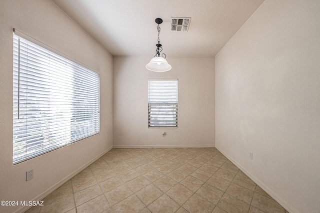 spare room featuring visible vents, plenty of natural light, and baseboards