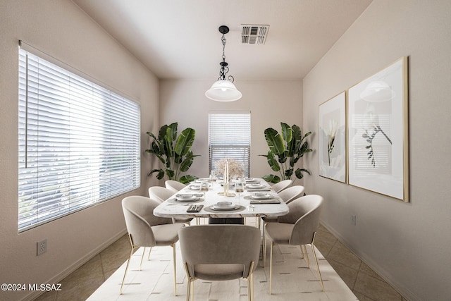 tiled dining area featuring a healthy amount of sunlight, visible vents, and baseboards