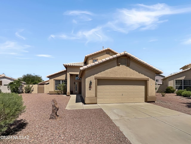 mediterranean / spanish-style home with driveway, a tile roof, a garage, and stucco siding