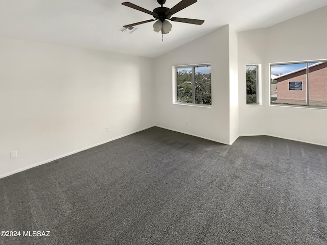 unfurnished room with lofted ceiling, visible vents, dark carpet, ceiling fan, and baseboards