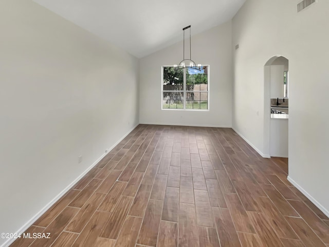 unfurnished dining area featuring arched walkways, wood finish floors, a chandelier, and visible vents