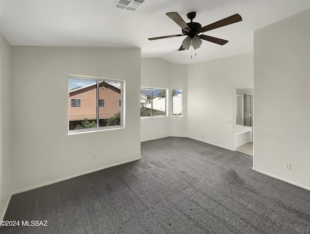 spare room with visible vents, dark carpet, vaulted ceiling, ceiling fan, and baseboards