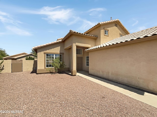 rear view of property with a patio area, fence, and stucco siding