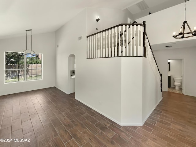 interior space with visible vents, a chandelier, wood tiled floor, stairs, and high vaulted ceiling