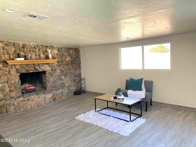 living room with a textured ceiling, light wood-type flooring, and a fireplace