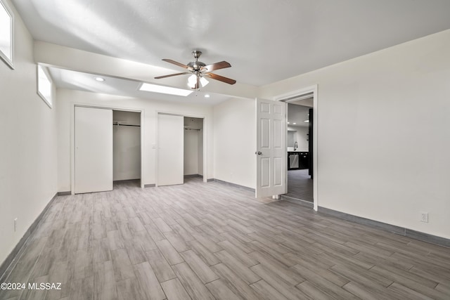 unfurnished bedroom with multiple closets, wood-type flooring, and ceiling fan