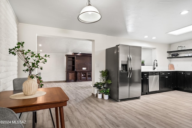 kitchen with crown molding, appliances with stainless steel finishes, light hardwood / wood-style flooring, and pendant lighting