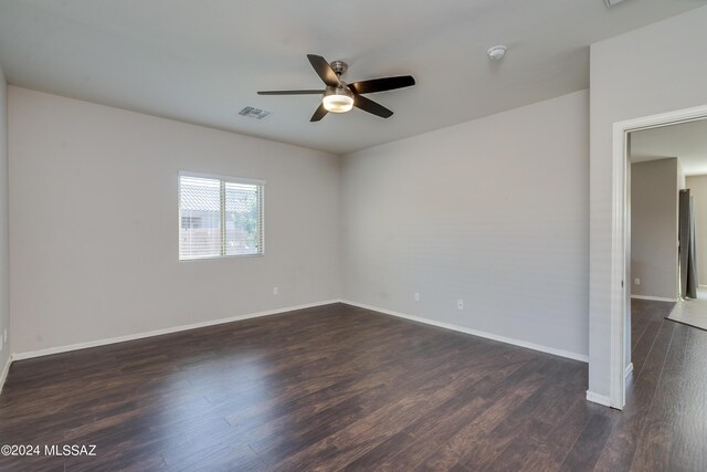 spare room featuring baseboards, visible vents, and dark wood-type flooring