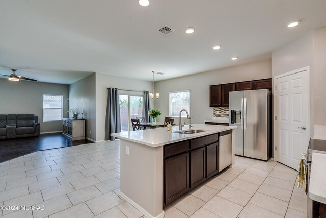 kitchen featuring light wood-type flooring, a kitchen island with sink, ceiling fan with notable chandelier, stainless steel appliances, and sink