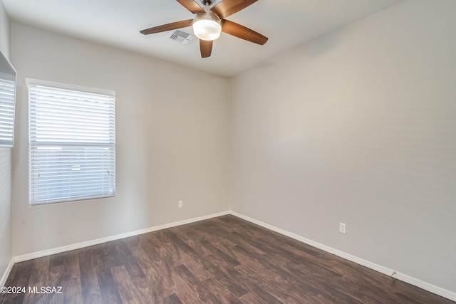 spare room featuring a ceiling fan, dark wood finished floors, visible vents, and baseboards