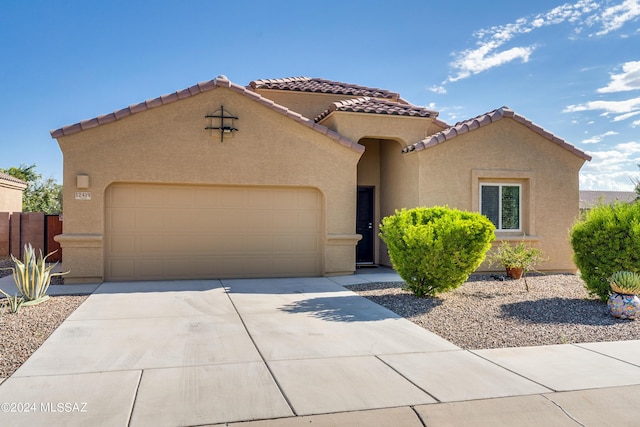 mediterranean / spanish home featuring a garage, driveway, a tiled roof, and stucco siding