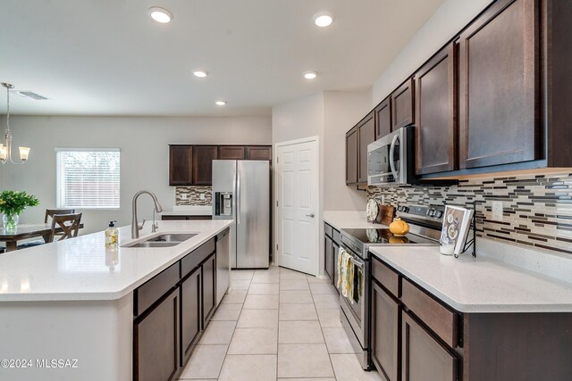 kitchen featuring hanging light fixtures, appliances with stainless steel finishes, a chandelier, sink, and tasteful backsplash