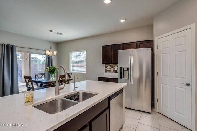 kitchen featuring an inviting chandelier, light stone countertops, appliances with stainless steel finishes, hanging light fixtures, and sink