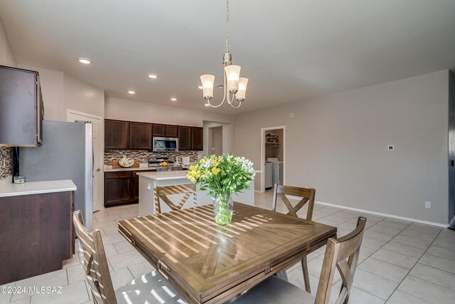 dining area featuring light tile patterned floors, washer and dryer, and a notable chandelier