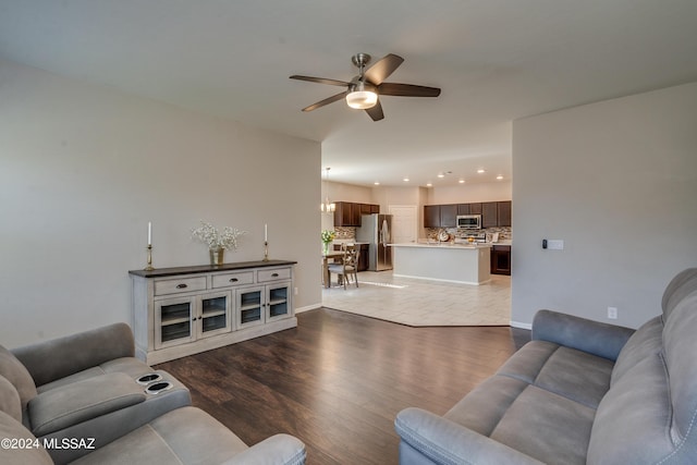 living area featuring ceiling fan with notable chandelier, baseboards, wood finished floors, and recessed lighting