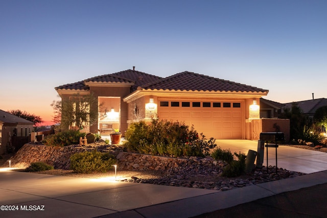 view of front of home featuring a tiled roof, an attached garage, driveway, and stucco siding