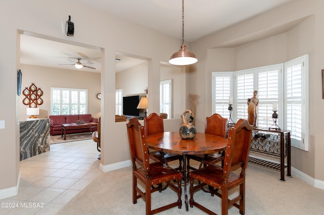 dining space featuring baseboards, light carpet, light tile patterned flooring, and a ceiling fan