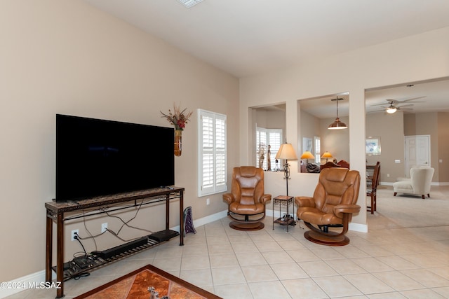 living area with ceiling fan, baseboards, and light tile patterned flooring