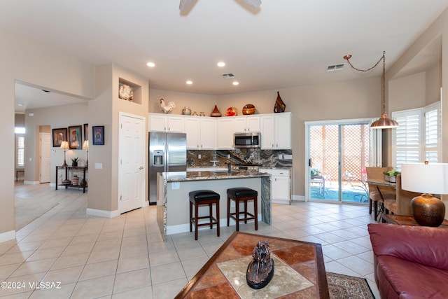 kitchen featuring visible vents, open floor plan, light tile patterned floors, decorative backsplash, and stainless steel appliances