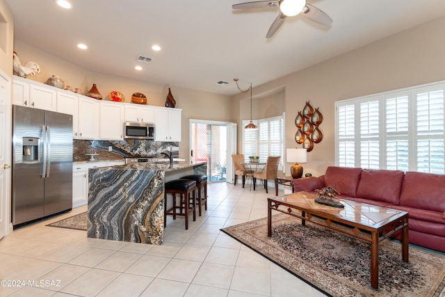 kitchen with visible vents, a kitchen breakfast bar, stainless steel appliances, light tile patterned floors, and decorative backsplash