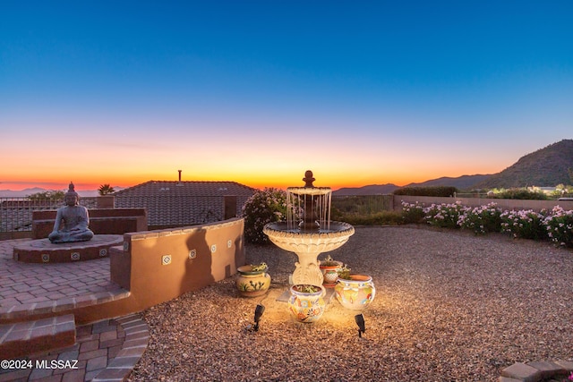 yard at dusk featuring a patio area and a mountain view