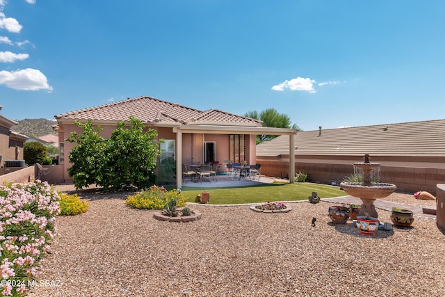 back of property with a fenced backyard, stucco siding, a tile roof, a patio area, and a lawn