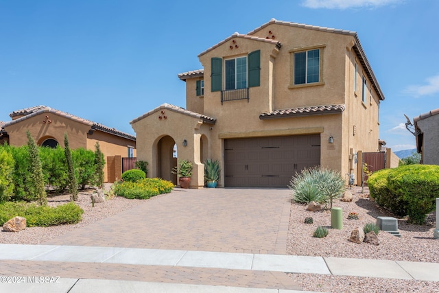 mediterranean / spanish-style house with decorative driveway, an attached garage, and stucco siding